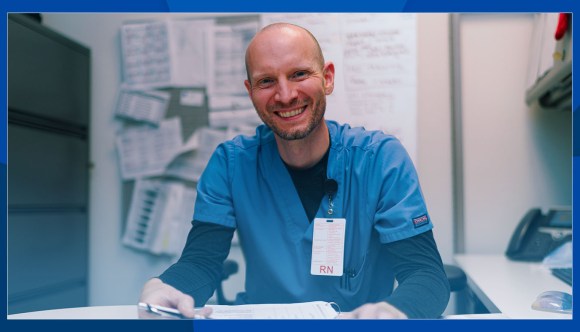 A registered nurse smiles while checking a patient record.