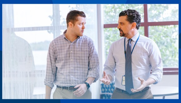Two professional men walk and talk during a Veteran’s interview.