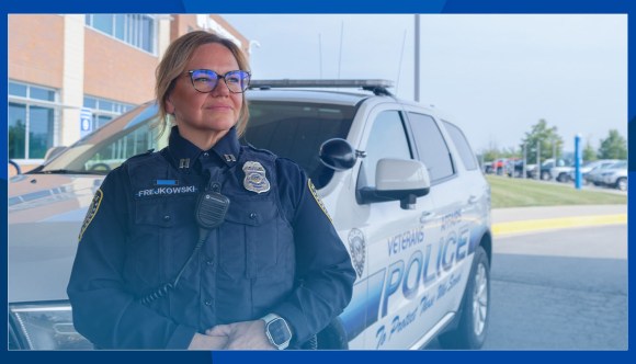 A police officer stands in front of a police car.
