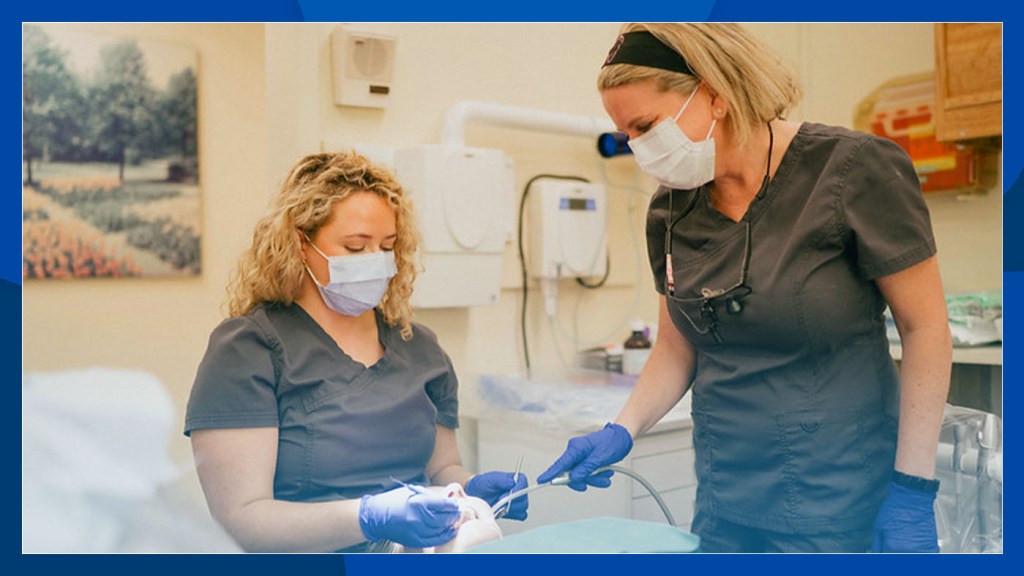 Two dental care providers clean a Veteran’s teeth.