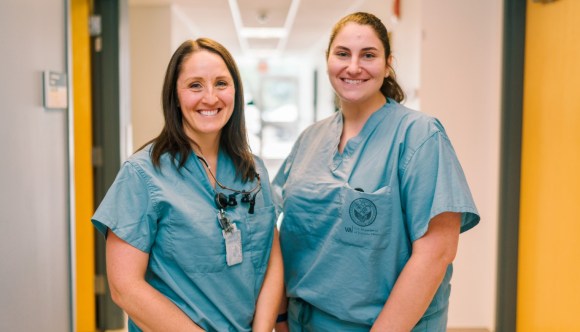 Two smiling VA health care workers in a hallway in a VA facility.