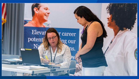 A seated VA recruiter highlights key information for a job seeker.