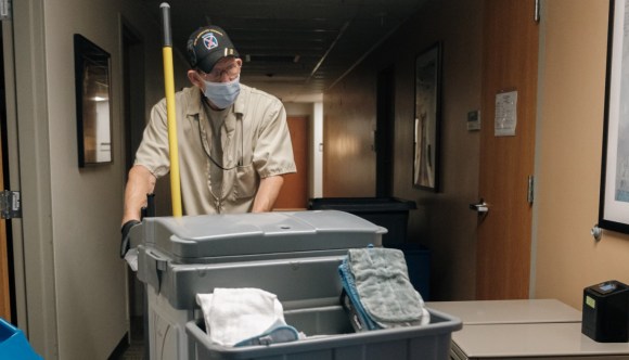 An environmental services technician takes his cleaning cart through the halls of a VA facility.