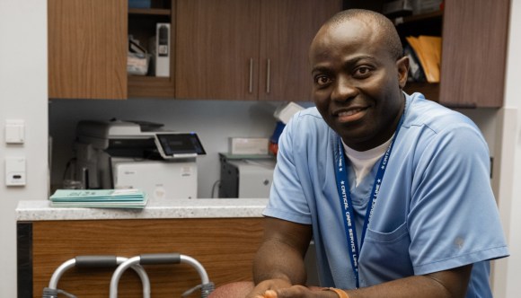 A Black man in scrubs in a VA exam room.