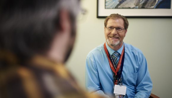 Man sitting across from another man interviewing him