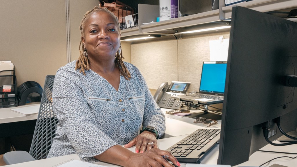 A smiling woman at a computer. 