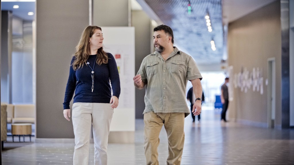 Two VA employees walk through a VA facility and discuss their work, engaging in the sense of community that serves as an additional employee benefit at VA.