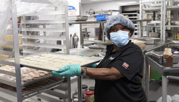 A VA food service worker prepares meals for distribution.