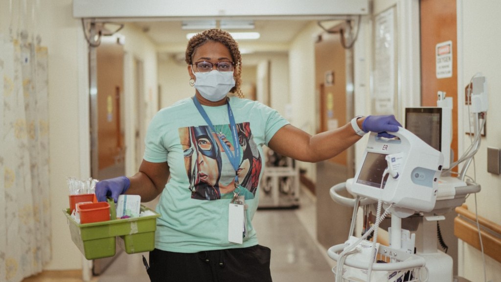 A VA employee stands in the hallway of a VA Medical Center, considering her reasons for working at VA.